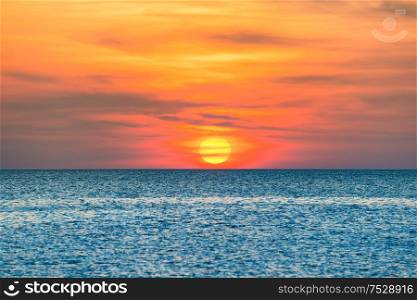 Nature landscape with beautiful dramatic orange sunset over blue rippled sea