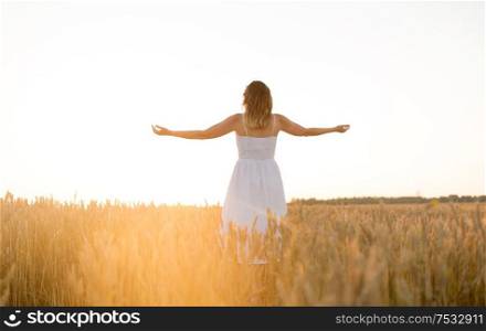 nature, people and happiness concept - happy young woman in white dress and enjoying freedom on cereal field in summer. happy woman enjoying freedom on cereal field