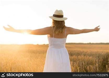 nature, people and happiness concept - happy young woman in white dress and straw hat and enjoying freedom on cereal field in summer. happy woman in straw hat on cereal field in summer