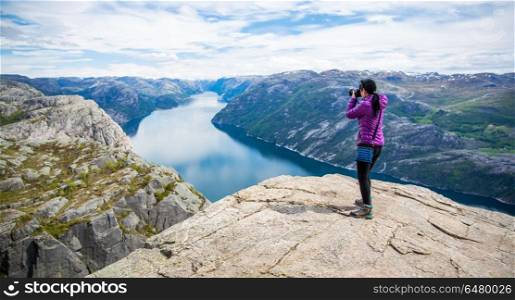 Nature photographer Beautiful Nature Norway Preikestolen or Prek. Nature photographer tourist with camera shoots while standing on top of the mountain. Beautiful Nature Norway Preikestolen or Prekestolen.