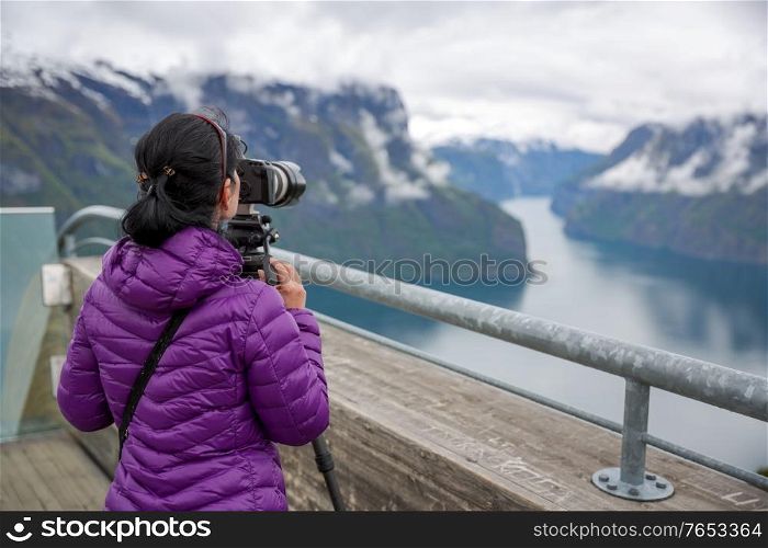 Nature photographer tourist with camera shoots. Stegastein Lookout. Beautiful Nature Norway.