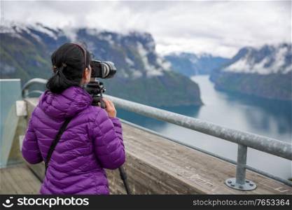 Nature photographer tourist with camera shoots. Stegastein Lookout. Beautiful Nature Norway.