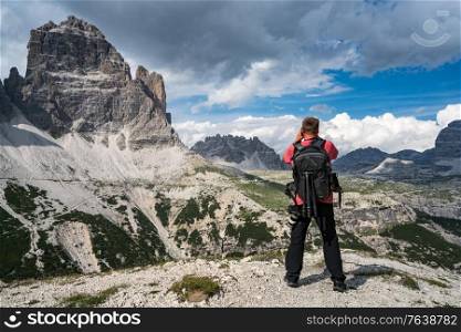 Nature photographer tourist with camera shoots while standing Italy Dolomites Alps.