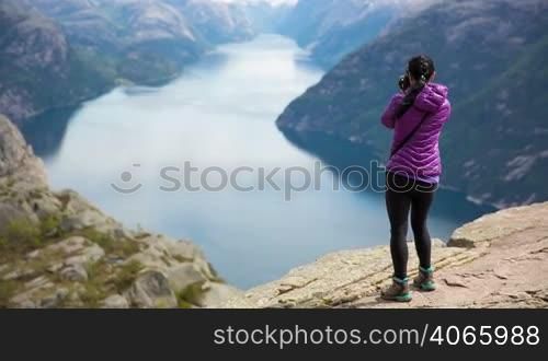 Nature photographer tourist with camera shoots while standing on top of the mountain. Beautiful Nature Norway Preikestolen or Prekestolen.