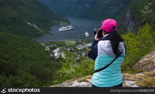 Nature photographer tourist with camera shoots while standing on top of the mountain. Beautiful Nature Norway Geiranger fjord.