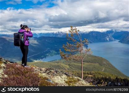 Nature photographer tourist with camera shoots while standing on top of the mountain. Beautiful Nature Norway.
