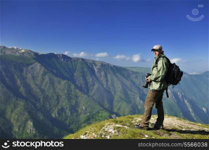Nature photographer with digital camera on top of the mountain
