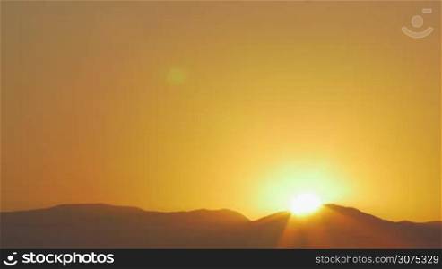 Nature scene of sunrise from behind the hills. Bright sun rising in golden sky