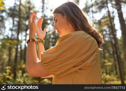 nature, spirituality and supernatural concept - young woman or witch performing magic ritual in forest. woman or witch performing magic ritual in forest