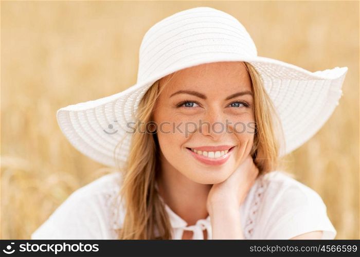 nature, summer holidays, vacation and people concept - close up of happy young woman in white dress and sun hat enjoying sun on cereal field