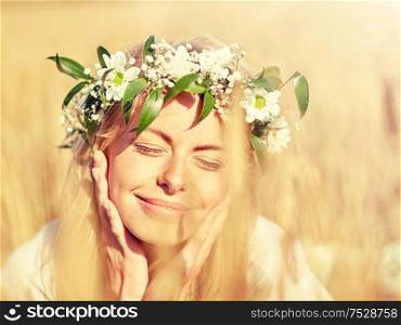 nature, summer holidays, vacation and people concept - face of happy smiling woman or teenage girl n in wreath of flowers on cereal field. happy woman in wreath of flowers on cereal field