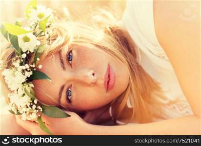 nature, summer holidays, vacation and people concept - face of happy woman in wreath of flowers lying on cereal field. happy woman in wreath of flowers on cereal field