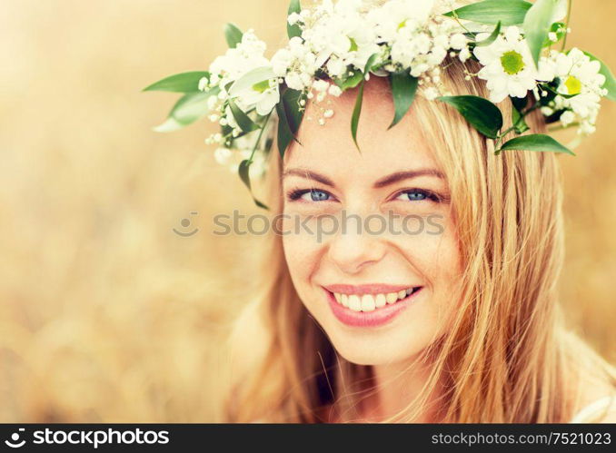 nature, summer holidays, vacation and people concept - face of happy woman in wreath of flowers. happy woman in wreath of flowers