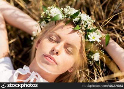 nature, summer holidays, vacation and people concept - happy smiling woman in wreath of flowers lying on straw