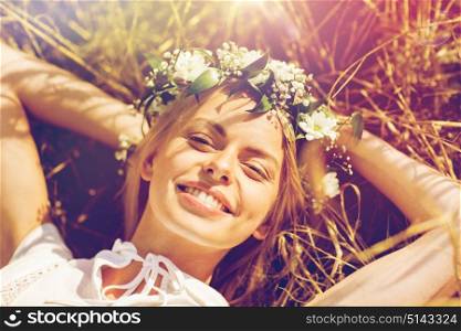nature, summer holidays, vacation and people concept - happy smiling woman in wreath of flowers lying on straw. happy woman in wreath of flowers lying on straw