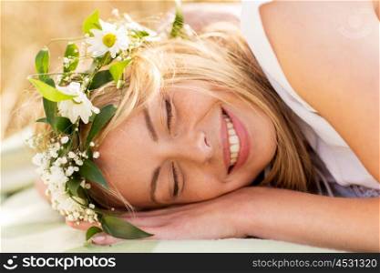 nature, summer holidays, vacation and people concept - happy smiling woman in wreath of flowers lying