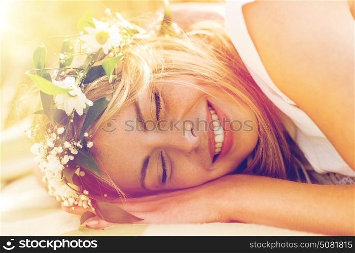 nature, summer holidays, vacation and people concept - happy smiling woman in wreath of flowers lying. happy woman in wreath of flowers lying