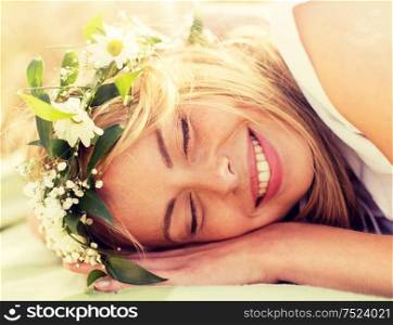 nature, summer holidays, vacation and people concept - happy smiling woman in wreath of flowers lying. happy woman in wreath of flowers lying