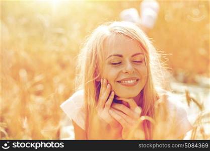 nature, summer holidays, vacation and people concept - happy smiling woman or teenage girl lying cereal field. happy woman or teen girl lying in cereal field. happy woman or teen girl lying in cereal field