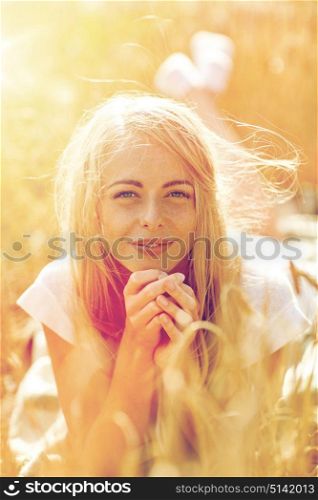 nature, summer holidays, vacation and people concept - happy smiling woman or teenage girl lying cereal field. happy woman or teen girl lying in cereal field