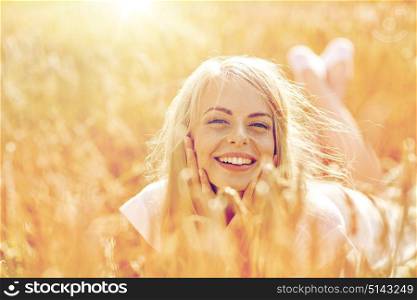 nature, summer holidays, vacation and people concept - happy smiling woman or teenage girl lying cereal field. happy woman or teen girl lying in cereal field