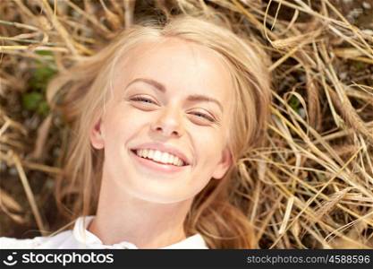 nature, summer holidays, vacation and people concept - happy smiling young woman or teenage girl lying and enjoying sun on cereal field