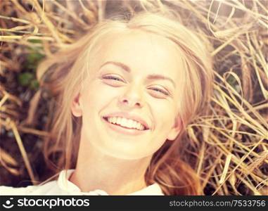 nature, summer holidays, vacation and people concept - happy smiling young woman or teenage girl lying and enjoying sun on cereal field. happy young woman lying on cereal field