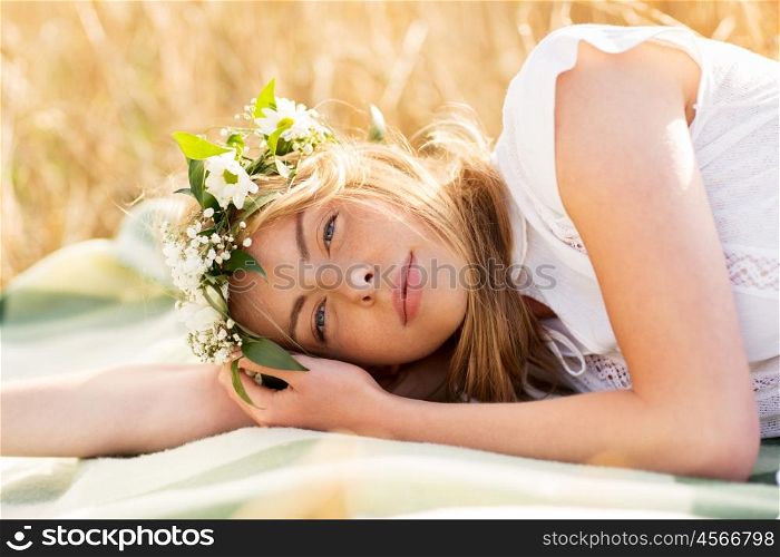 nature, summer holidays, vacation and people concept - happy woman in wreath of flowers lying