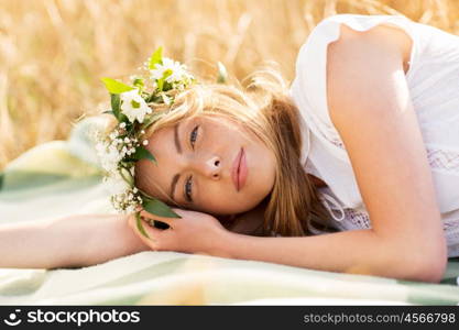 nature, summer holidays, vacation and people concept - happy woman in wreath of flowers lying