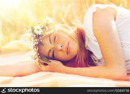 nature, summer holidays, vacation and people concept - happy woman in wreath of flowers lying. happy woman in wreath of flowers on cereal field. happy woman in wreath of flowers on cereal field