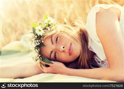 nature, summer holidays, vacation and people concept - happy woman in wreath of flowers lying. happy woman in wreath of flowers on cereal field