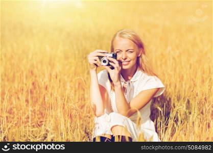 nature, summer holidays, vacation and people concept - happy woman taking picture with film camera outdoors. happy woman with film camera in wreath of flowers. happy woman with film camera in wreath of flowers