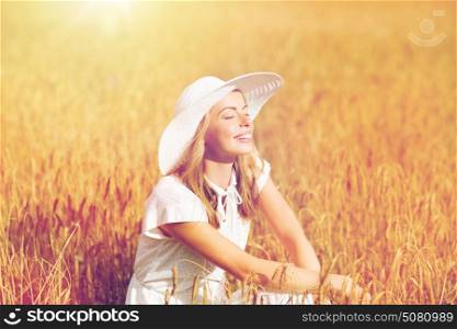 nature, summer holidays, vacation and people concept - happy young woman in white dress and sun hat enjoying sun on cereal field. happy young woman in sun hat on cereal field