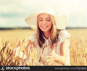 nature, summer holidays, vacation and people concept - happy young woman in white dress and sun hat enjoying sun on cereal field. happy young woman in sun hat on cereal field