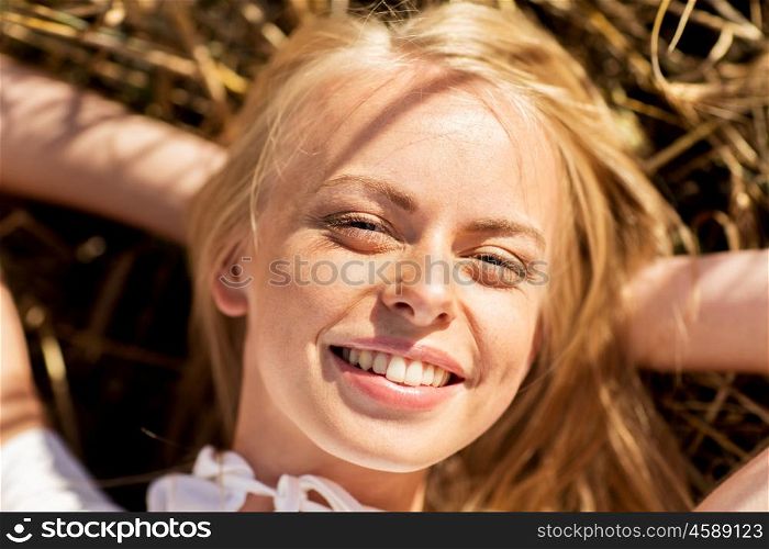nature, summer holidays, vacation and people concept - happy young woman lying and enjoying sun on cereal field