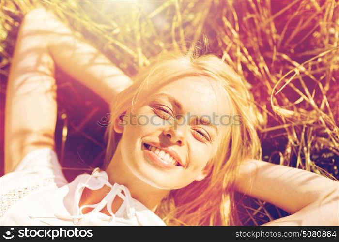 nature, summer holidays, vacation and people concept - happy young woman lying and enjoying sun on cereal field. happy young woman lying on cereal field
