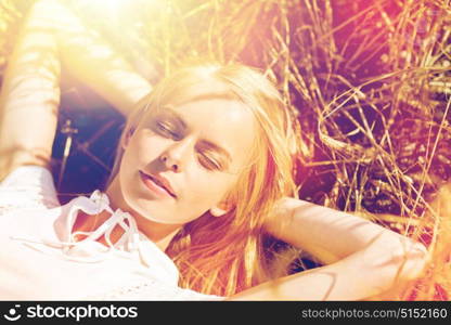 nature, summer holidays, vacation and people concept - happy young woman lying and enjoying sun on cereal field or hay. happy young woman lying on cereal field or hay