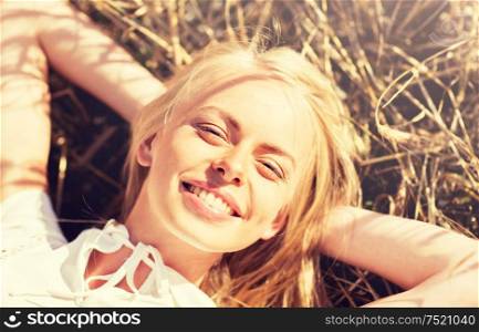 nature, summer holidays, vacation and people concept - happy young woman lying and enjoying sun on cereal field. happy young woman lying on cereal field