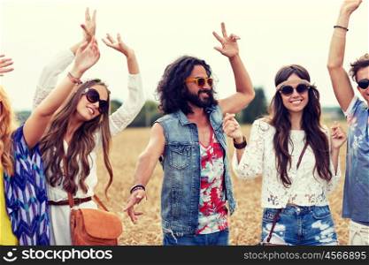 nature, summer, youth culture and people concept - happy young hippie friends dancing on cereal field