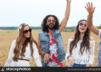nature, summer, youth culture and people concept - happy young hippie friends dancing on cereal field