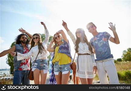 nature, summer, youth culture and people concept - happy young hippie friends dancing outdoors