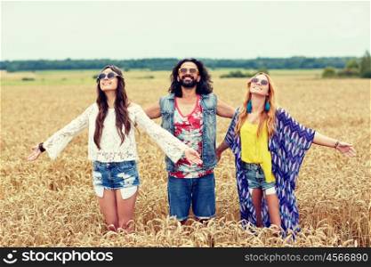 nature, summer, youth culture and people concept - smiling young hippie friends on cereal field enjoying freedom