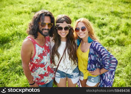 nature, summer, youth culture and people concept - smiling young hippie friends in sunglasses on green field