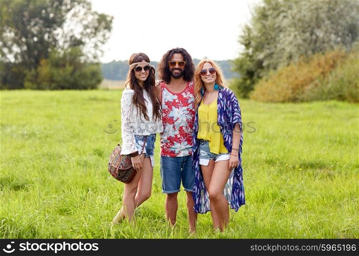 nature, summer, youth culture and people concept - smiling young hippie friends in sunglasses on green field