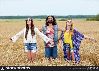 nature, summer, youth culture and people concept - smiling young hippie friends on cereal field enjoying freedom