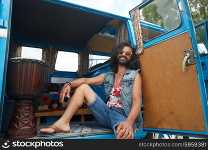 nature, summer, youth culture and people concept - smiling young hippie man with tom-tom drum in minivan car