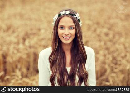 nature, summer, youth culture and people concept - smiling young hippie woman wearing flower wreath on cereal field