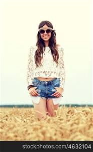 nature, summer, youth culture and people concept - smiling young hippie woman in sunglasses on cereal field