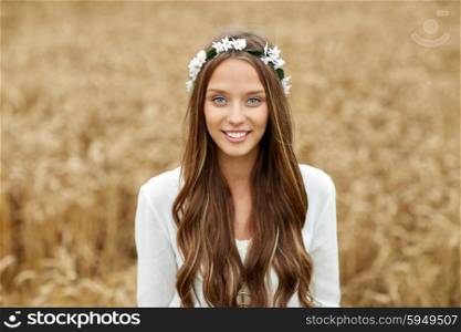 nature, summer, youth culture and people concept - smiling young hippie woman wearing flower wreath on cereal field