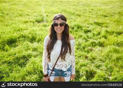 nature, summer, youth culture and people concept - smiling young hippie woman in sunglasses on green field